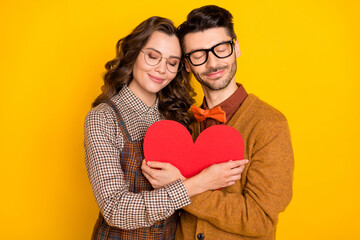 Portrait of attractive cheerful amorous couple friends friendship embracing heart shape isolated on bright yellow color background