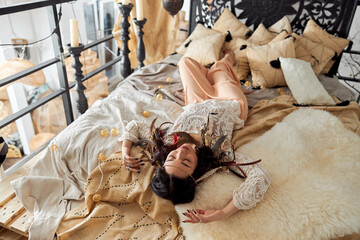 Mature beautiful dark haired woman in shamanic ethnic outfit in bali style decorated room