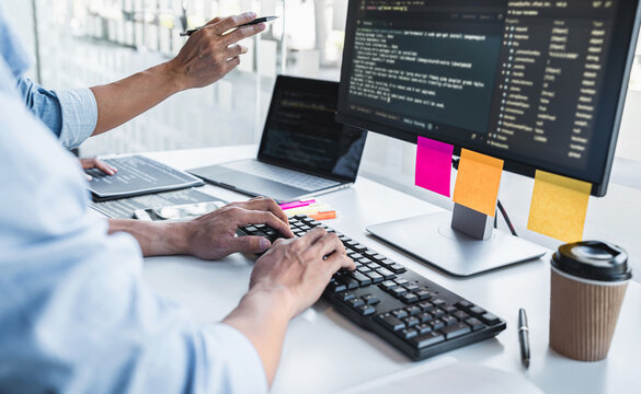 Two professional programmer cooperating and working on web site project in a software developing on desktop computer at company, codes and typing data code, Programming with HTML, PHP and javascript