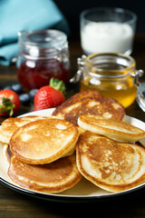 Blini served with strawberry jam, honey, sour cream and fresh berries. Dark wooden table, high resolution