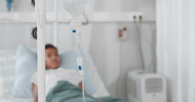 Focus on drip in hospital room with blurry patient child on hospital bed