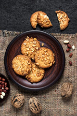 Homemade peanut cookies on a brown plate with raw peanuts in background