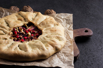 Homemade galette pie with apples, elder berries and walnuts decorated with fresh cowberry