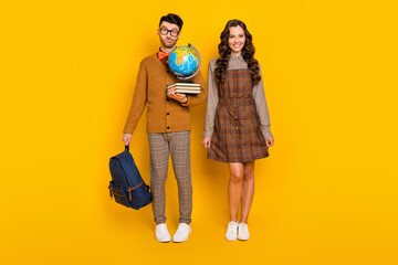 Full body photo of brunette couple wear plaid dress pants bow-tie hold bag globe books nerd isolated on yellow color background