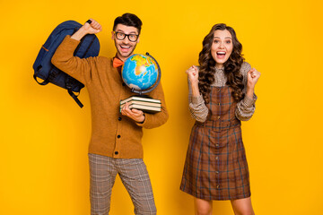 Photo of brunette cheerful couple hold globe books backpack winner isolated on yellow color...