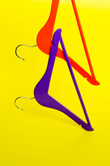 Red and violet wooden hanger floating in the air. Yellow background with copy space