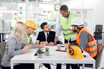Multiracial team of businesspeople and architects working with drawings inspection