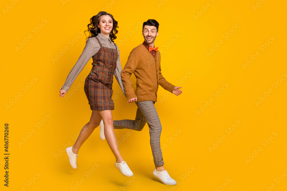 Poster full body profile side photo of happy couple jump up go empty space smile isolated on yellow color b