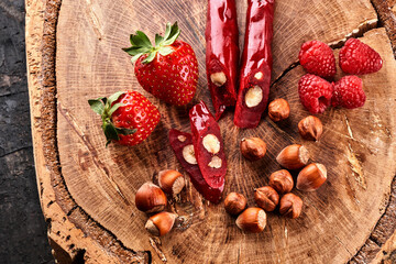 slicing Churchkhela, strawberries and nuts on a wooden background, top view, serving