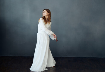 Fototapeta premium Portrait of an attractive woman in a white dress on a gray background in full growth Copy Space