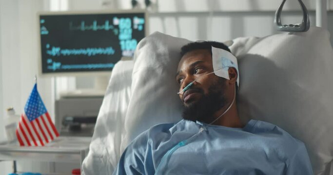 African male patient lying on medical bed in hospital ward