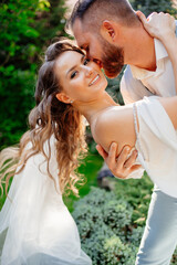 groom bent over bride in dance in park. wedding photo shoot in garden.