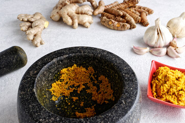 Pestle and mortar and  bowl with garlic, ginger and turmeric paste with ingredients. Indian cuisine.