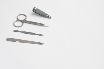 Metal manicure set, tweezers, scissors, file and spatula on white background, copy space