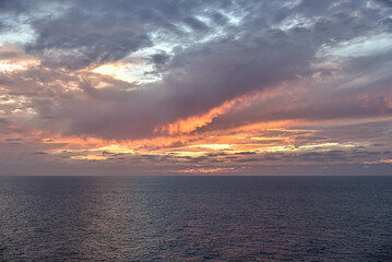 Sunset over the calm sea in a cloudy sky. Abstract and dramatic sunset sky.