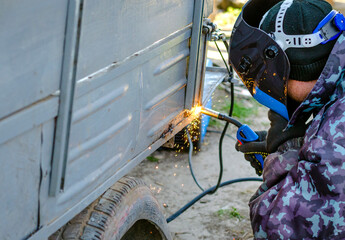 welder works at home in a protective mask without gloves