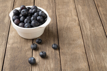 Blueberries on a bowl over wooden table with copy space