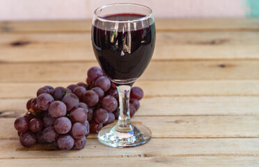 Bunch of pink grape and glass of natural juice on wooden background