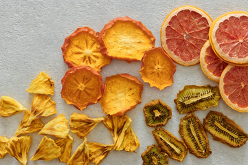 Naklejka na ściany i meble Dried dehydrated fruits on bright background with copy space. Healthy natural flavor snacks: pineapple, persimmon, kiwi and grapefruit chips.
