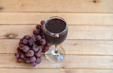 Bunch of pink grape and glass of natural juice on wooden background