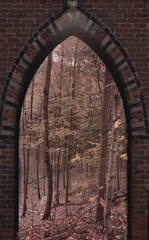 Old entrance gate made of bricks inviting to a fall background 
