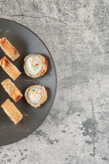 Black plate of delicious fried hot rolls on marble background