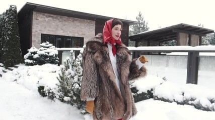 Beautiful young woman in fur. Winter and autumn fashion. Beauty sexy model girl in red head scarf . Stylish woman in rich real fur coat in snowy backyard.