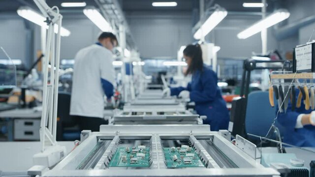 Modern High-Tech Electronics Factory Moving Manufacturing Conveyor: Professionals Doing Precision Work Assemble Circuit Boards, Processors, Microchips, Semiconductors. High-Quality Production Line