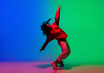 Inspiration. Stylish sportive girl dancing hip-hop in stylish clothes on colorful background at dance hall in neon light. Youth culture, movement, style and fashion, action. Fashionable bright - obrazy, fototapety, plakaty
