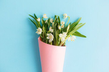 Spring flowers bouquet in pink paper cone on blue background. Happy Mothers day. Happy womens day