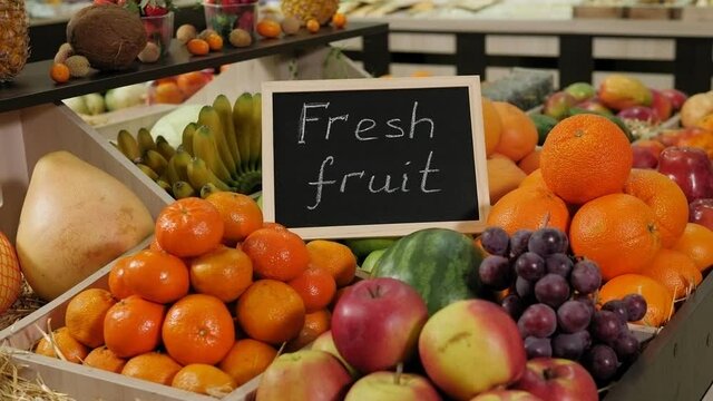 Close-up of various fruits in boxes on the shelves in a grocery store, next to there is a nameplate with the inscription FRESH FRUITS.