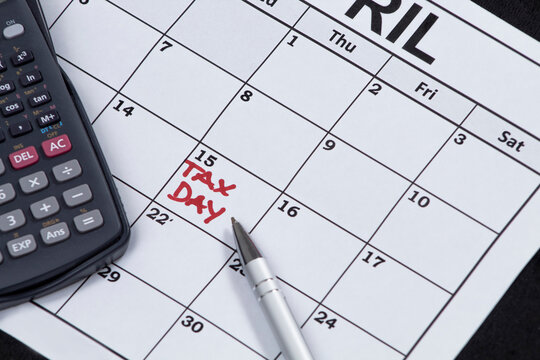 Tax day image with an april calendar a pen a calculator in coins for tax time