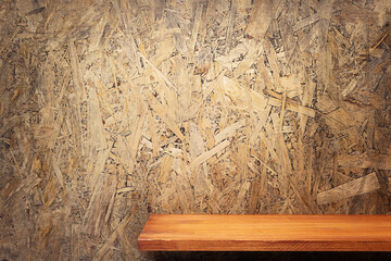 Wooden shelf or tabletop near chipboard wall background. Front view of shelf