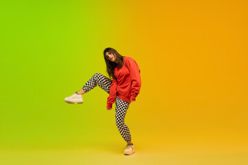 Energy. Stylish sportive girl dancing hip-hop in stylish clothes on colorful background at dance...