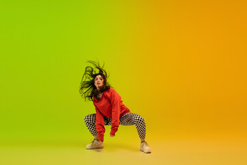 Dynamic. Stylish sportive girl dancing hip-hop in stylish clothes on colorful background at dance...
