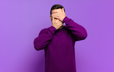 handsome adult blond man covering face with both hands saying no to the camera! refusing pictures...