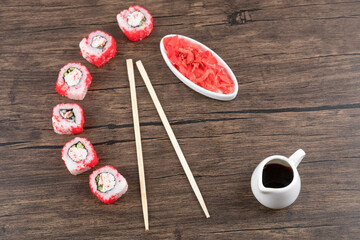 California sushi rolls, pickled ginger and soy sauce on wooden surface