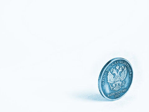 Light Blue Background On The Theme Of The Russian Economy And Finance With Place For Text. A 5 Five Ruble Shabby Coin From Circulation Stands On Its Edge. Tinted Backdrop With Copy-space. Macro