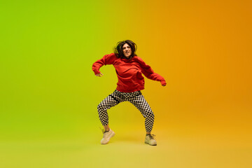 Fototapeta na wymiar Action. Stylish sportive girl dancing hip-hop in stylish clothes on colorful background at dance hall in neon light. Youth culture, movement, style and fashion, action. Fashionable bright portrait.