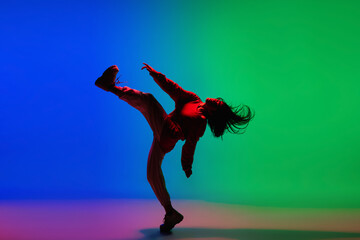 Street. Stylish sportive girl dancing hip-hop in stylish clothes on colorful background at dance hall in neon light. Youth culture, movement, style and fashion, action. Fashionable bright portrait.