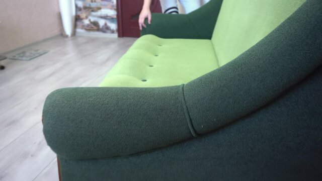 A man rearranges furniture in a room, moving the sofa, changes in the interior, a guy changes the situation in an apartment