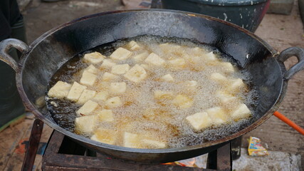 Tofu is being fried with lots of oil