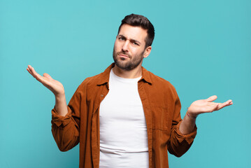 handsome adult blond man looking puzzled, confused and stressed, wondering between different...