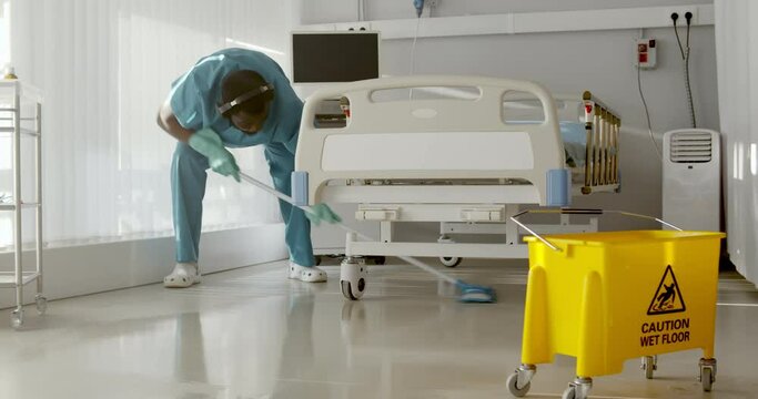 Afro-american male nurse cleaning patient room in modern hospital