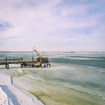 A short wooden pier on the shore of the frozen sea