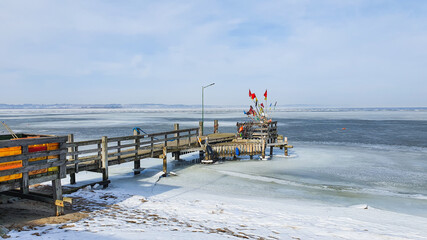 A short wooden pier on the shore of the frozen sea