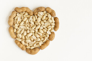 Salted peeled peanuts in a heart shape isolated on white background.