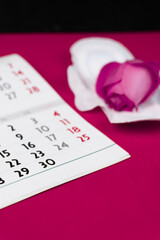 Close-up of female calendar of periods for checking the days of menstruation, isolated on a red background. Medical healthcare gynecological concept. Copy space.