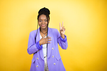 Young african american business woman smiling swearing with hand on chest and fingers up, making a...