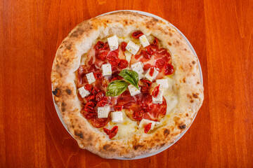 Pizza napoletana con mozzarella, pomodori secchi, formaggio e capocollo